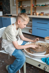 Boy learning pottery at a workshop, hands shaping clay on a pottery wheel