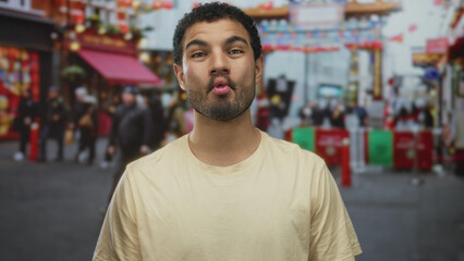 Young man smiling with visible lips wearing a yellow tshirt on a busy city street in daylight;...