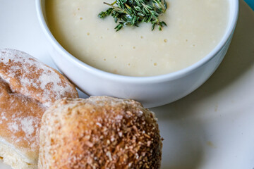 Traditional Bowl Of Chicken Soup With Thyme Garnish And Soft White Bread Rolls