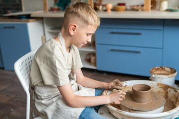 Boy learning pottery at a workshop, hands shaping clay on a pottery wheel