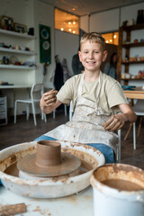 Boy learning pottery at a workshop, hands shaping clay on a pottery wheel