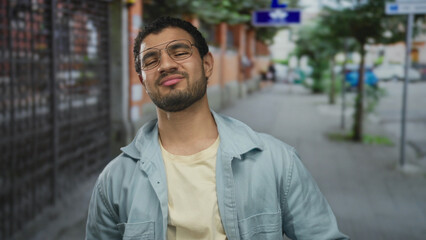 Fototapeta premium Man with glasses tilting his head back and smiling in a light blue jacket on a sunlit busy city street; optimism joy confidence.