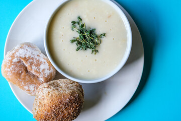 Traditional Bowl Of Chicken Soup With Thyme Garnish And Soft White Bread Rolls