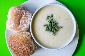 Traditional Bowl Of Chicken Soup With Thyme Garnish And Soft White Bread Rolls