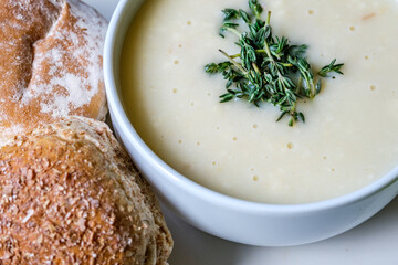 Traditional Bowl Of Chicken Soup With Thyme Garnish And Soft White Bread Rolls