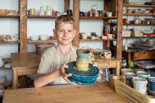Proud boy showing finished clay cup at pottery studio