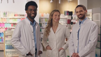 Multiracial people team doctors men woman in pharmacy drugstore professional health care workers in medical coats pharmacist physician therapist team African Caucasian male female looking at camera
