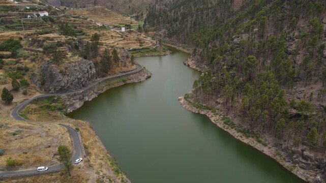 Cars driving along winding road by los perez dam in gran canaria