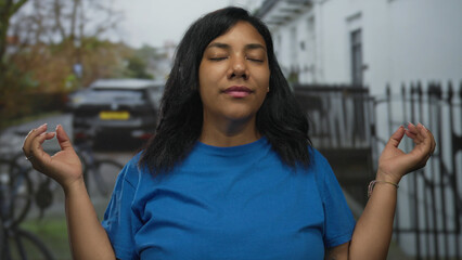 Woman meditating with closed eyes wearing blue shirt and fingertips touching mudra gesture on...