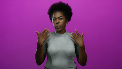Woman with afro hairstyle waving hands over pink background expressing relief in a playful gesture