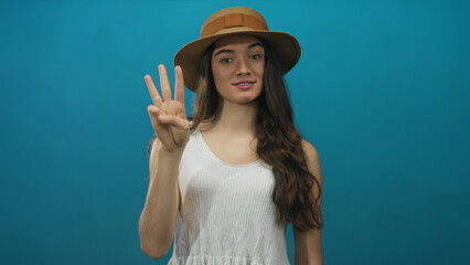 Teenage hispanic woman holds hand displaying sequential finger count in studio session; counting...
