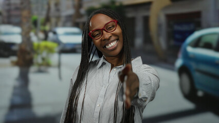 Woman offering handshake on sunny urban street wearing glasses and a striped shirt with a cheerful...