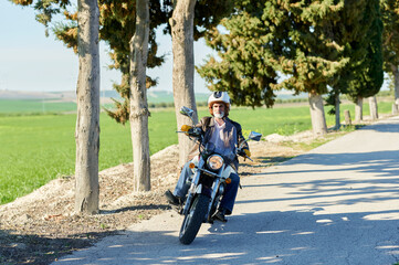 Senior motorcyclist riding his motorbike on a countryside road