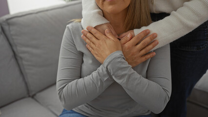 Mother and daughter embracing lovingly in living room, displaying family bond, woman sitting and...