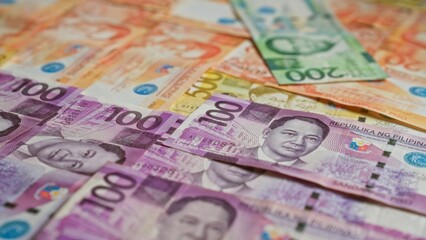 Philippine banknotes scattered, showcasing various denominations including 100 peso and 200 peso bills.