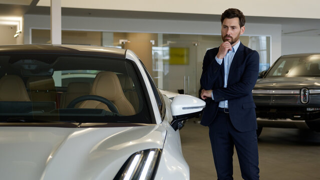 Caucasian man businessman touching car thinking client buyer automobile choosing choose rental service male buying pondering vehicle salon decision transport store thoughtful guy customer dealership