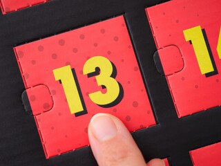 Woman finger pointing at the number 13 on an advent calendar.
