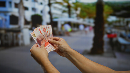 Man holding norwegian krone banknotes on a bustling urban street, highlighting concepts of business...