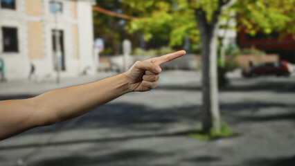 Hand of a man pointing in an outdoor city street with blurred background depicting urban...