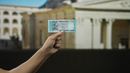 Man holding bangladeshi taka banknote on city street, showcasing currency in a busy urban outdoor...
