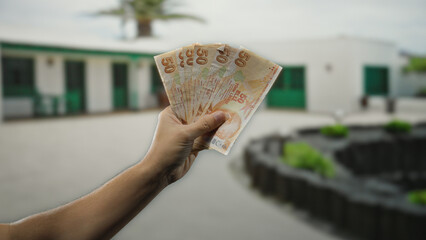 Man holding turkish lira banknotes on a sunny city street showcasing vibrant outdoor urban scene...