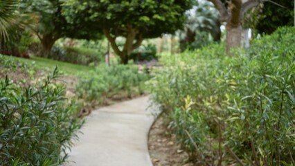 Blurred view of a lush tropical garden pathway surrounded by greenery in a luxury resort setting with defocused foliage creating a dreamy, peaceful atmosphere.