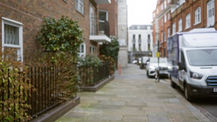 Defocused urban street scene in chelsea, london featuring blurred buildings and parked cars along a quiet sidewalk on an overcast winter day.