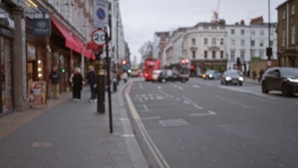Blurred winter street in london with people walking past shops and iconic red bus in the background, capturing a typical urban scene in the united kingdom during autumn.
