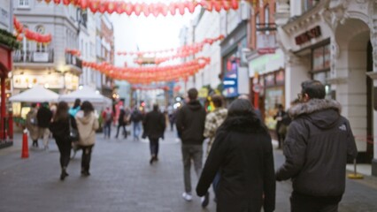 Blurred people strolling on chinatown street in london under red lanterns displaying winter...