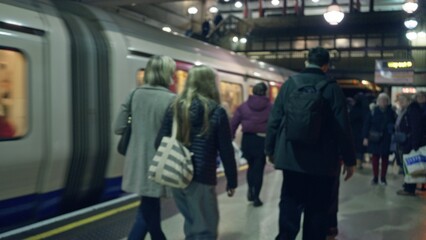 People walking on a bustling london subway platform with blurred train and defocused crowd...
