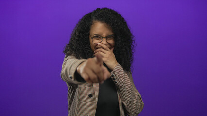 Woman pointing with laughter on a purple background, implying a playful and humorous moment,...