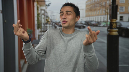 Man wearing grey sweater shows middle finger gesture on street outside urban brick buildings while...