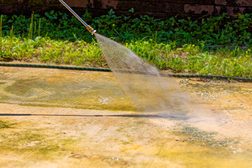 Cleaning concrete in the garden with a pressure washer