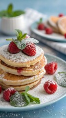Delicious Stack of Powdered Sugar Pancakes with Fresh Raspberries and Mint Garnish