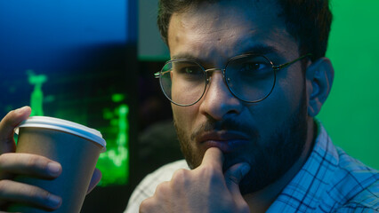Close up face Indian Arabian man holding cup drinking coffee male thoughtful guy programmer coder...