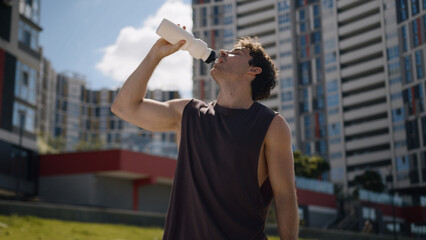 Caucasian man athlete male guy sport drinking bottle water refresh workout city outside fitness...