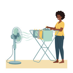 Woman drying clothes with standing fan in cozy home setting  