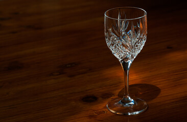 An empty crystal glass standing on a wooden table.