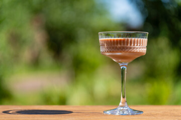 Delicious chocolate cocktail served in an elegant crystal glass with a green summer garden...