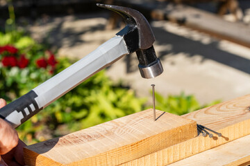 Worker using a hammer an metal nail into a wooden board, closeup. Hand tool for working....