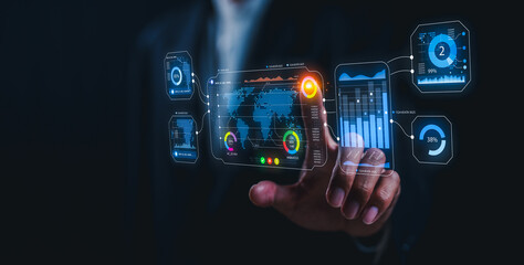 A person interacts with futuristic transparent digital interfaces displaying data analytics and global information in a dark setting.