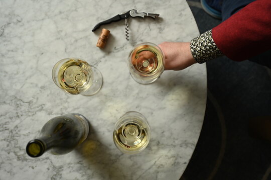 Top down table of white wine and bottle with persons hand
