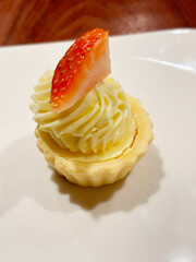 Closeup of a single mini strawberry tart, served on a white porcelain plate.