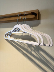 4 modern and sleek cloth hangers, hanging on a single rod attached to the wall.