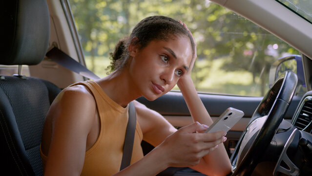 Shocked African American woman bad news message worried girl car automobile auto vehicle mobile phone smartphone social media problem nervous businesswoman business upset sad female close mouth inside