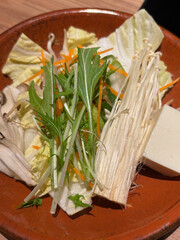 Closeup of a plate of raw vegetables and enoki mushroom, suitable to be used in Asian cuisine such...