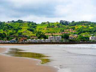 View of Hondarribia, Spain from Plage d’Hendaye, France—lush hills, coastal homes, and beach...