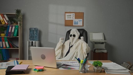 Halloween businessman ghost in white sheet works with papers and rejoicing. Happy halloween...