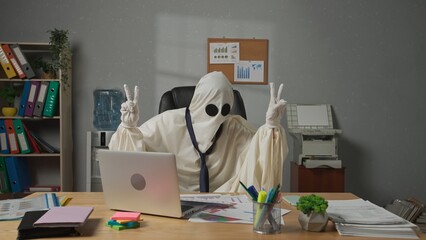 Halloween businessman ghost in white sheet works with papers and rejoicing. Happy halloween...