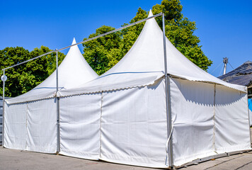 Bright blue tent stands in a bustling market area during the day, showcasing a space for vendors...